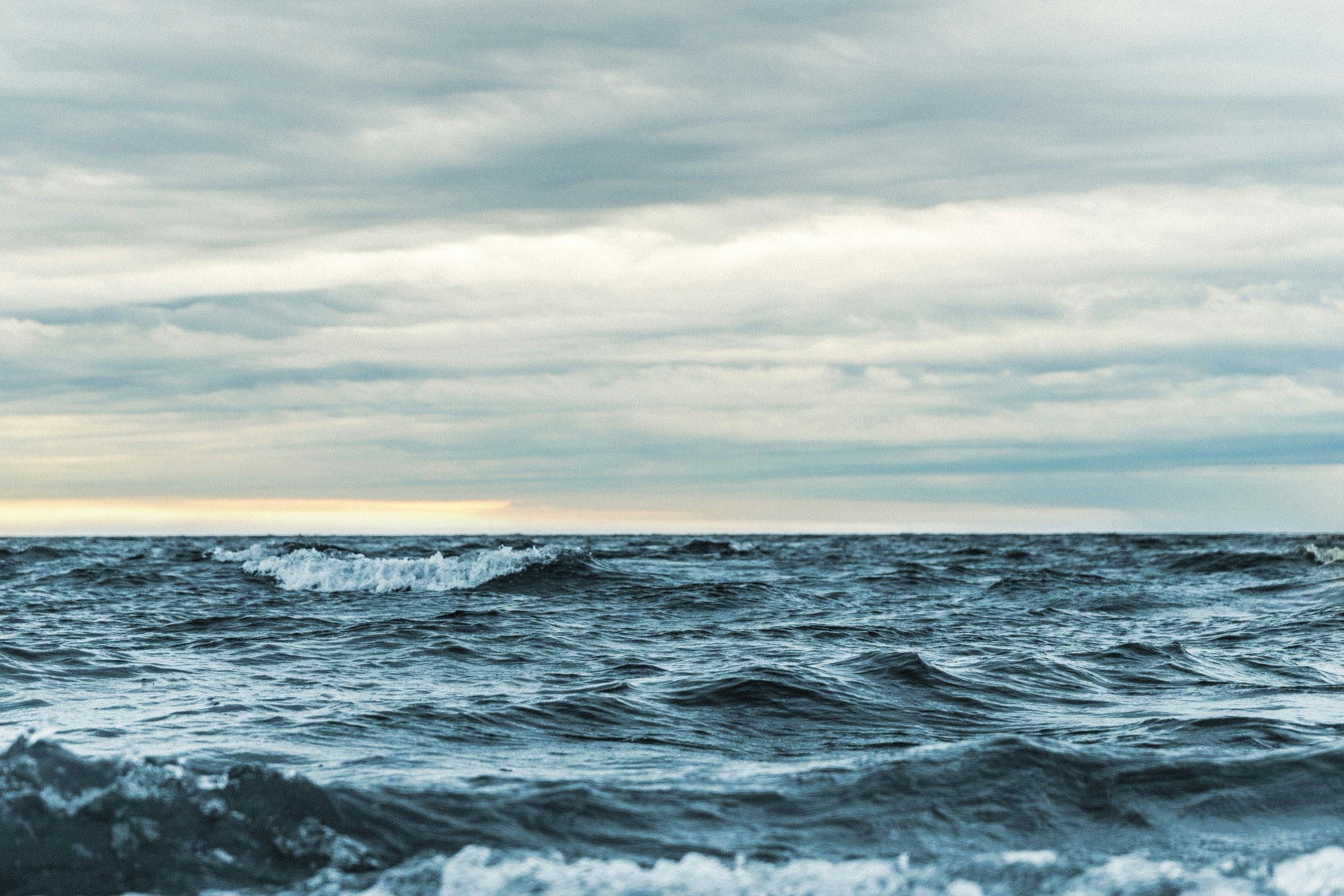 Ocean waves under a cloudy sky at dusk